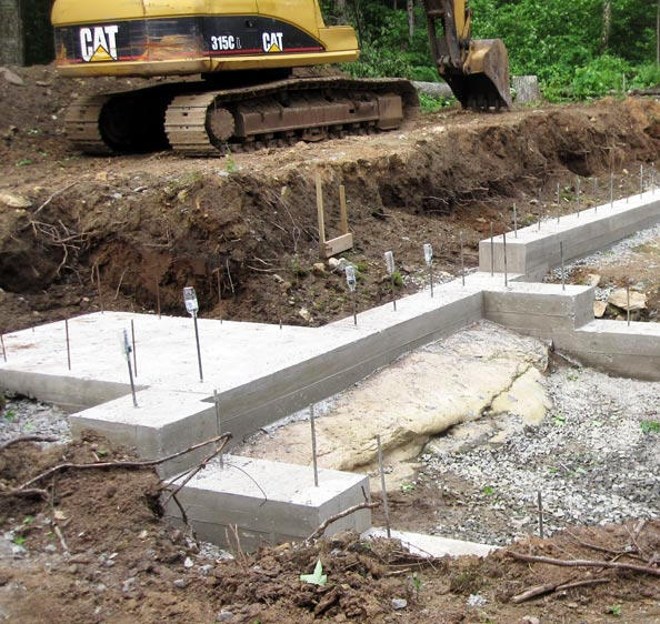 Main Photo Excavator next to fresh foundation.